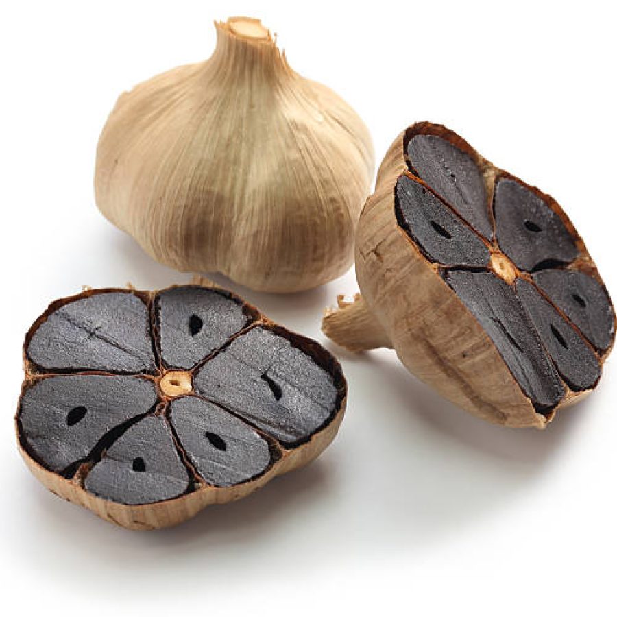 black garlic bulbs and cloves on white background